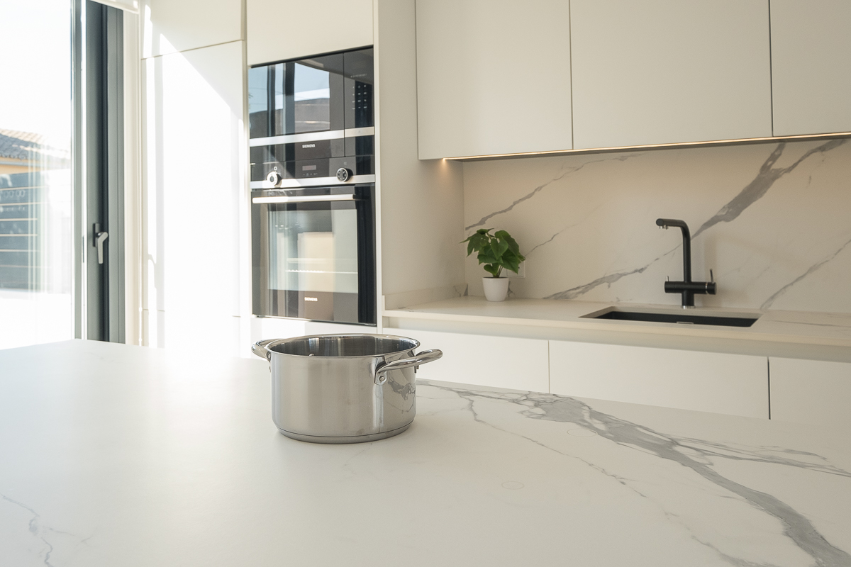 Cocina blanca moderna con isla y porcelánico Statuario Light