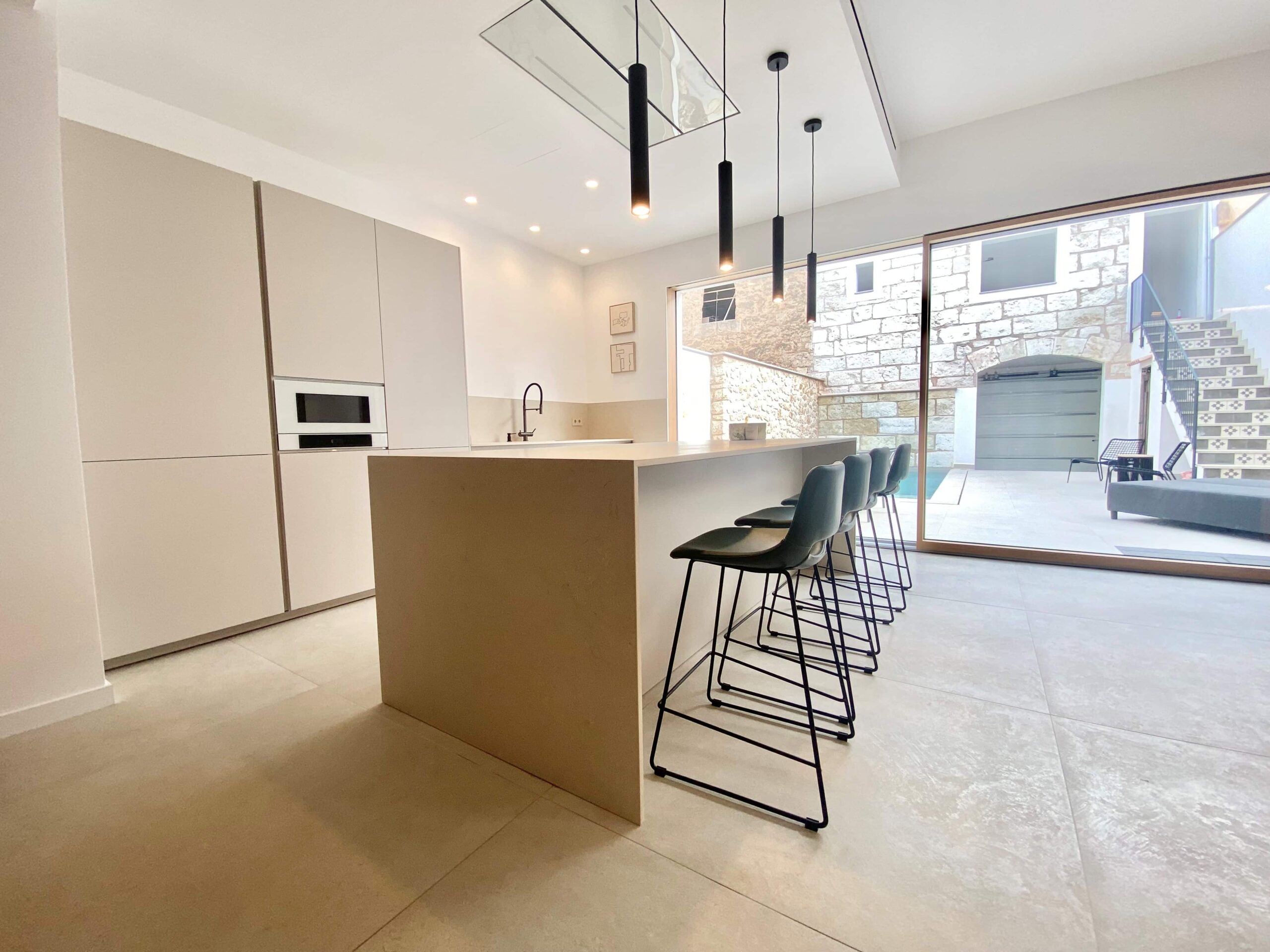 Cocina con isla central en porcelánico Trani Beige con placa Cooking Surface integrada